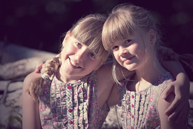 Dívky-dvojčata, držící se kolem ramen
